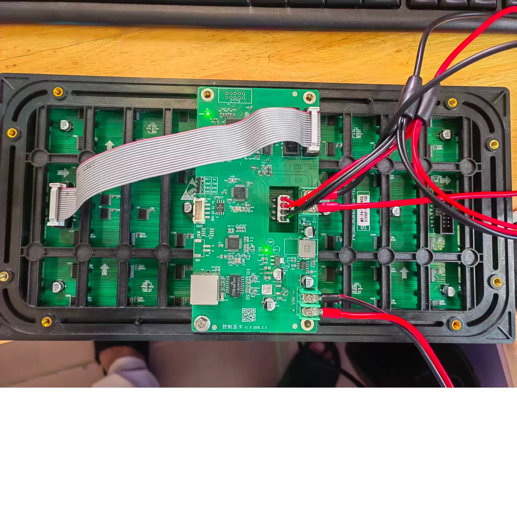 A control board mounted on the back of an LED display module, connected to the module’s HUB75 header and power terminals.
